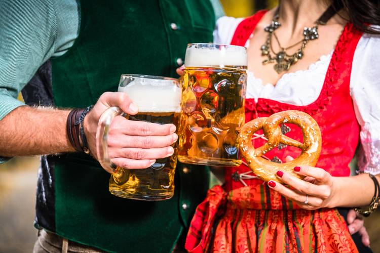 Hände, die Bier und Bretzeln halten, Ausschnitt bayrische Tracht Hands holding Beer and Pretzels, detail of bavarian Tracht