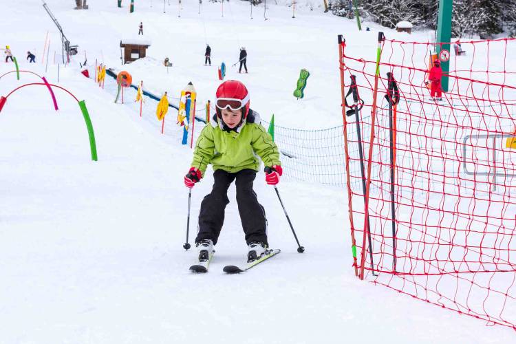 Little kid enjoying skiing in ski school