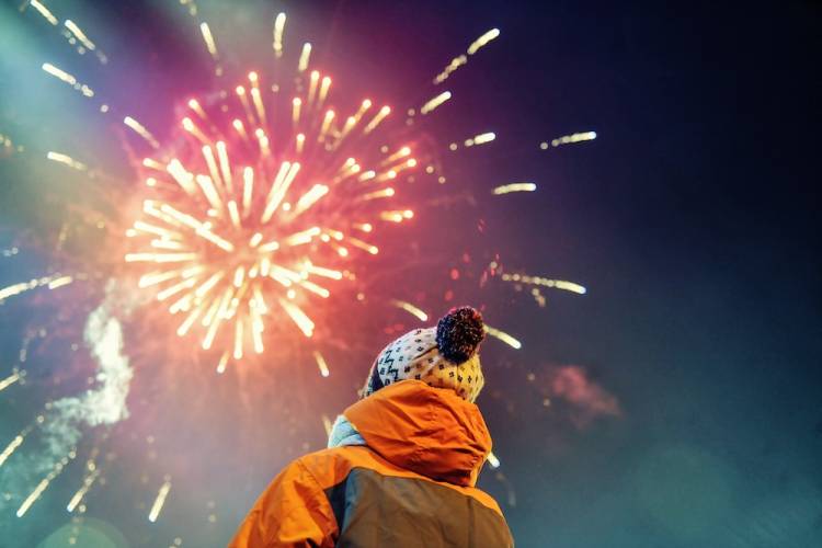 person in winter gear watching fireworks