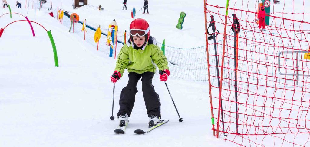 Little kid enjoying skiing in ski school